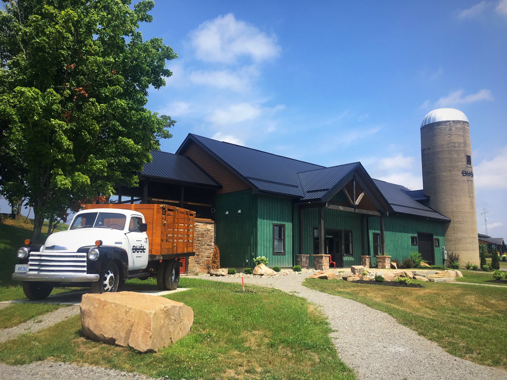 A white truck sits in front of a green barn at a cidery.