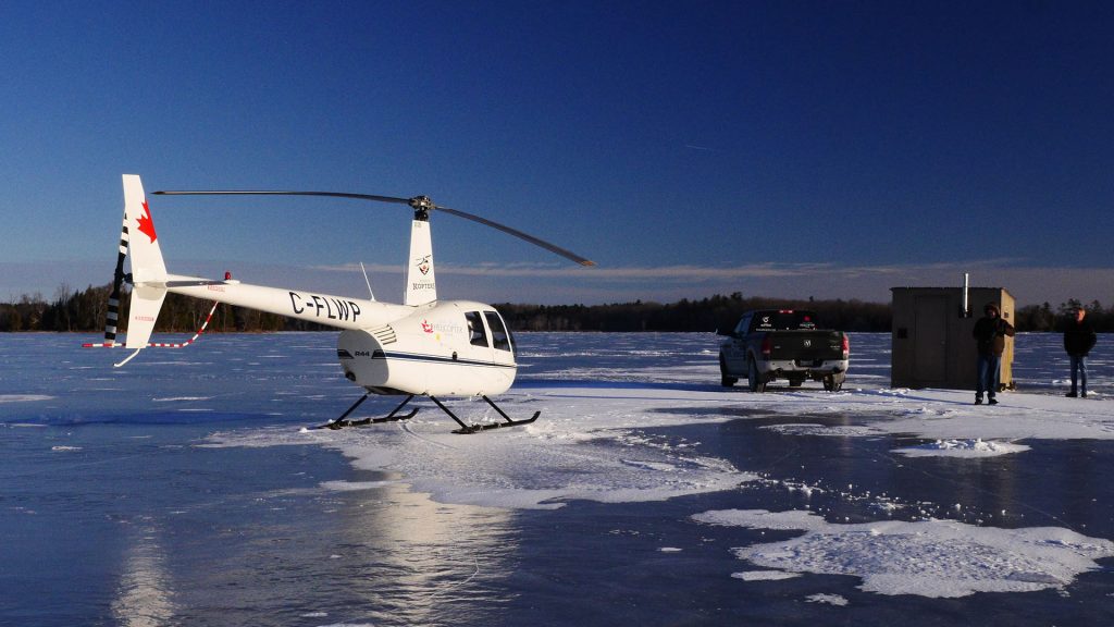 A helicopter sits on a frozen lake.