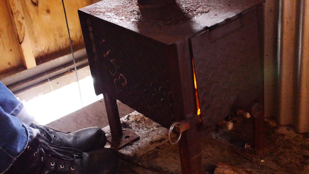 A pair of boots warms by a fireplace.