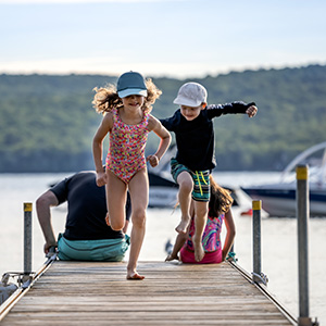 Two children in bathing suits run on a dock.