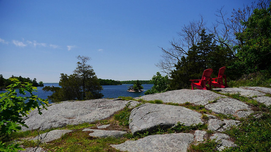 Two red chairs overlooking the St. Lawrence River.