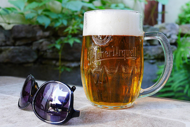 A beer beside a pair of sunglasses.