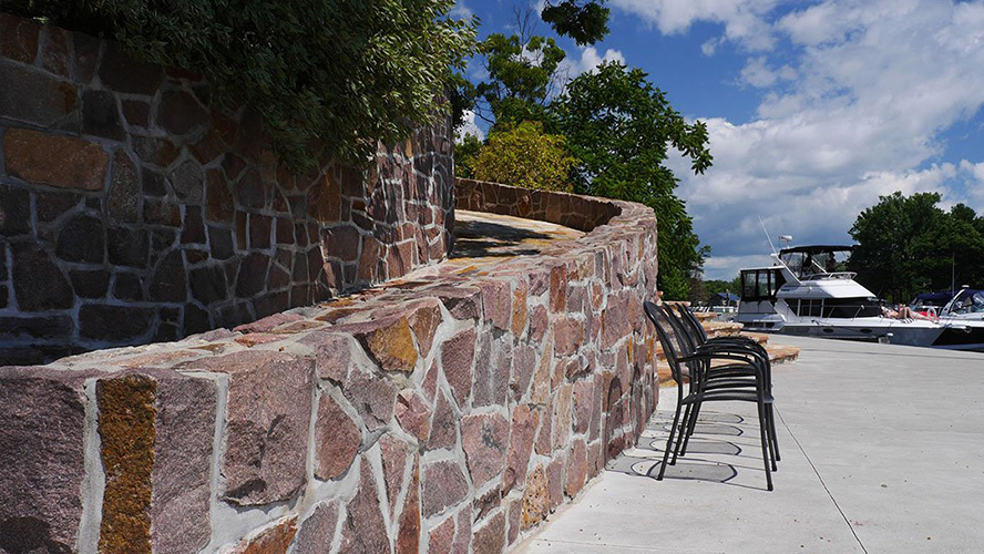 A stone wall lines a sidewalk.