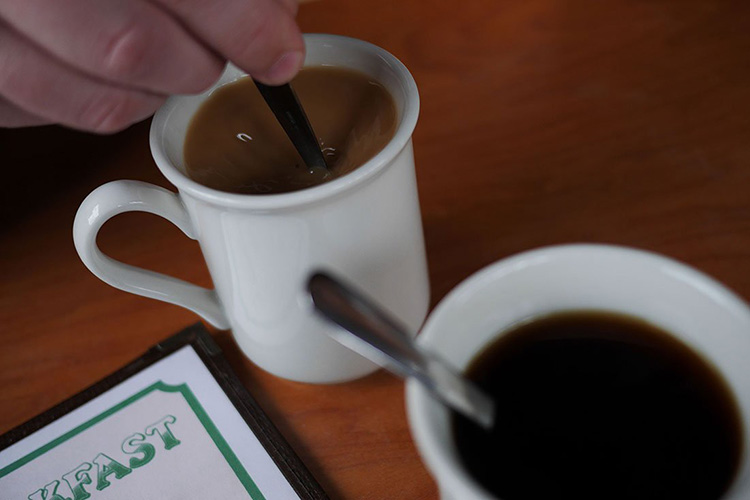 Two cups of coffee beside menus. 