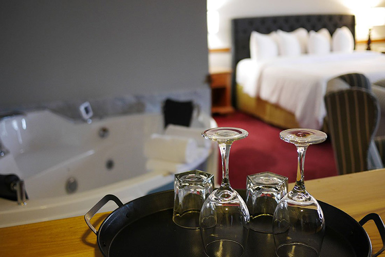 Wine glasses beside a soaker tub.