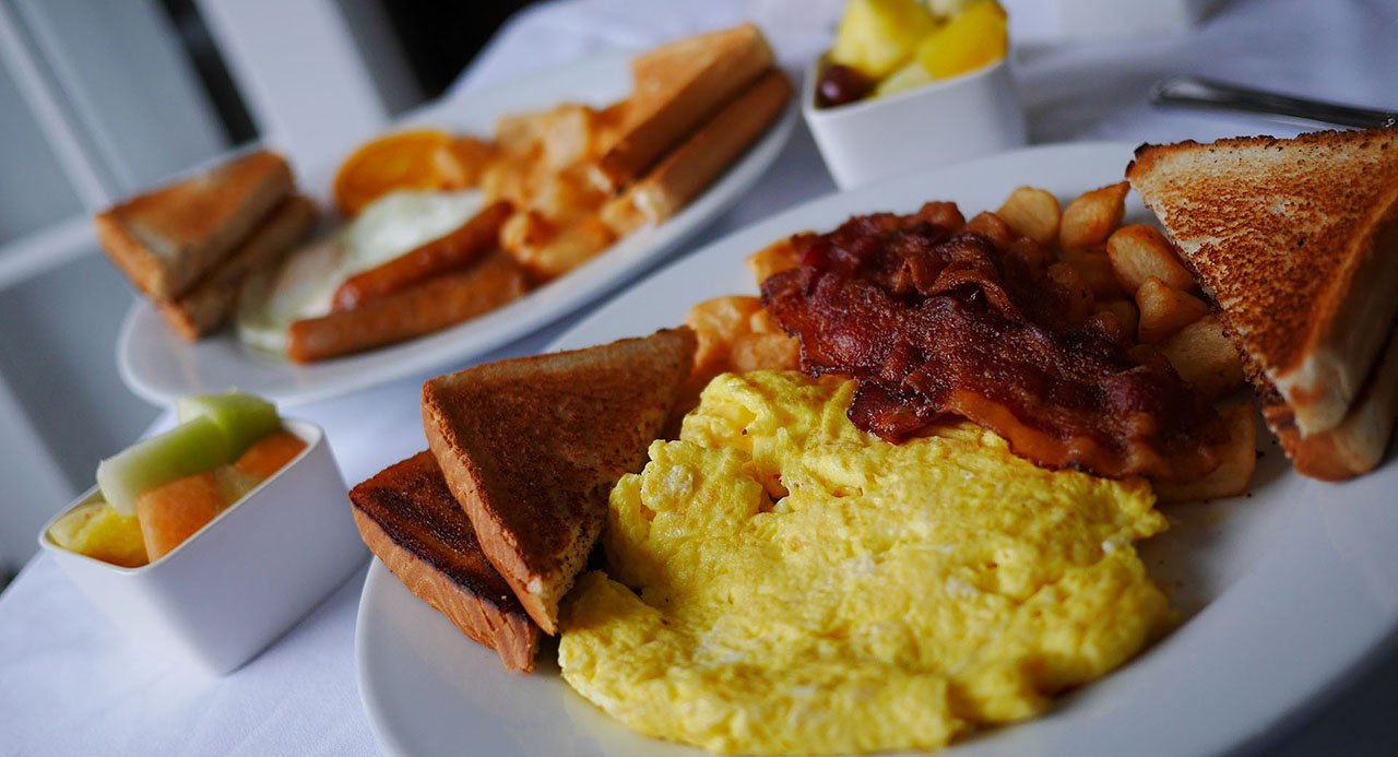 A breakfast of bacon and eggs on a white plate.