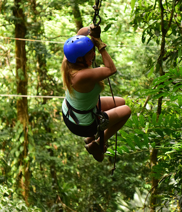 A person in a blue helmet rappelling through the trees.