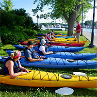 A row of kayaks on the banks of a river.