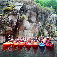 A row of kayaks in front of a rock face.